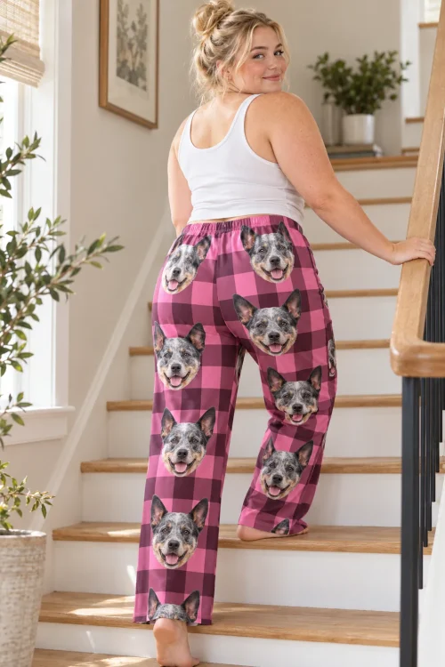 Woman glancing back on a staircase in pink plaid australian cattle dog pajamas, faces on the back of the legs