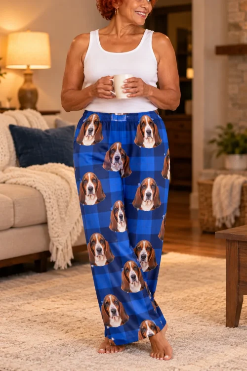 Woman with a mug standing by a living room fireplace in blue plaid pajama pants printed with basset hound faces