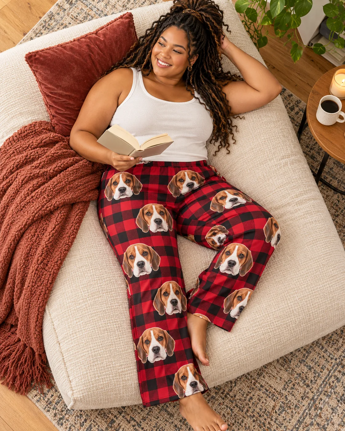 Custom Beagle Pajama Pants for Women — red plaid detail | GenzOutfit Woman reading on a big floor cushion in red plaid beagle pajamas, seen from above with a candle and coffee
