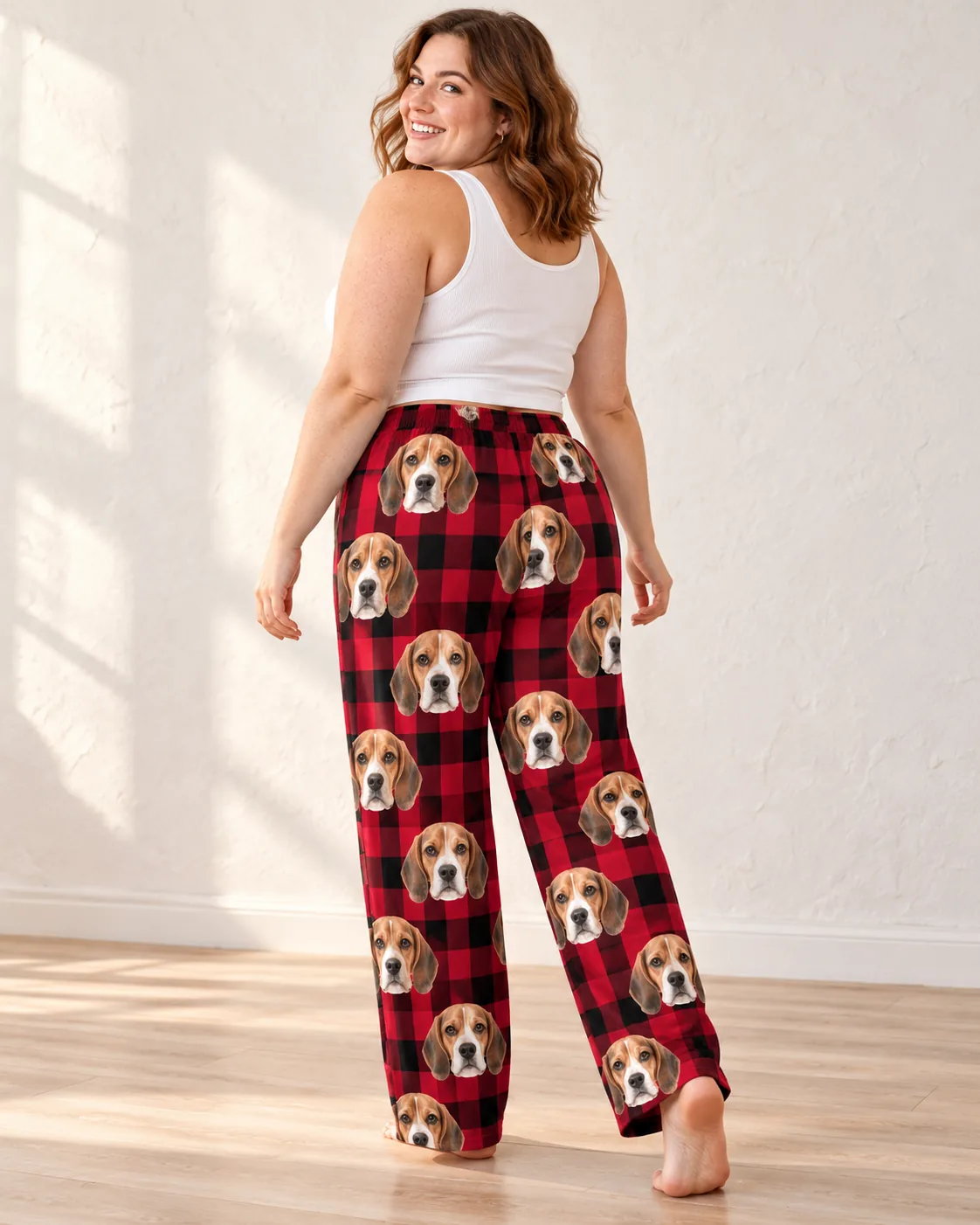 Woman glancing back over her shoulder in red plaid beagle pajamas womens, faces down the back of both legs, sunny studio