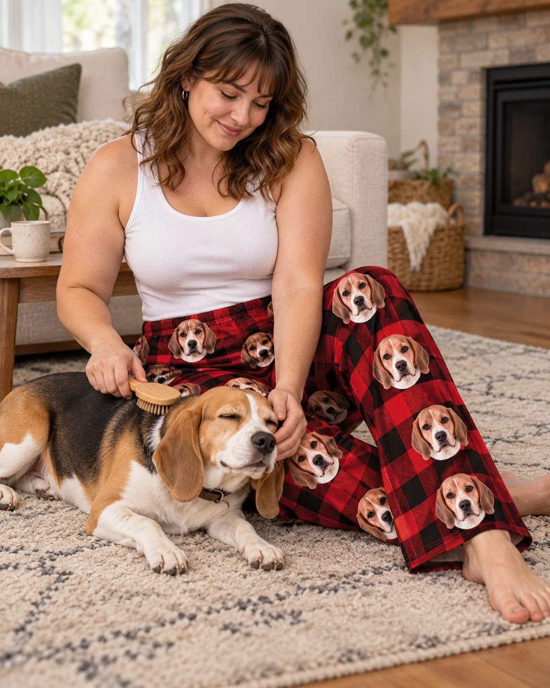 Custom Beagle Pajama Pants for Women — red plaid with pet | GenzOutfit Woman brushing her sleepy beagle on the living room rug in red plaid beagle pajama pants near the fireplace
