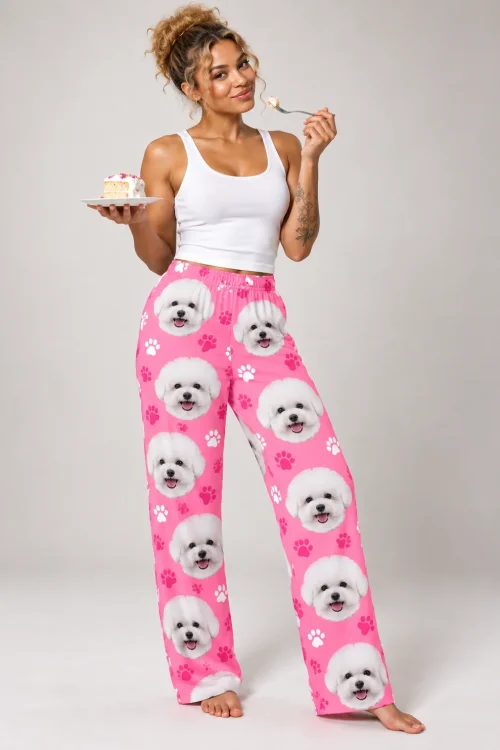 Woman in a white tank top holding a slice of cake and a fork, in pink paws bichon frise pajamas, gray studio