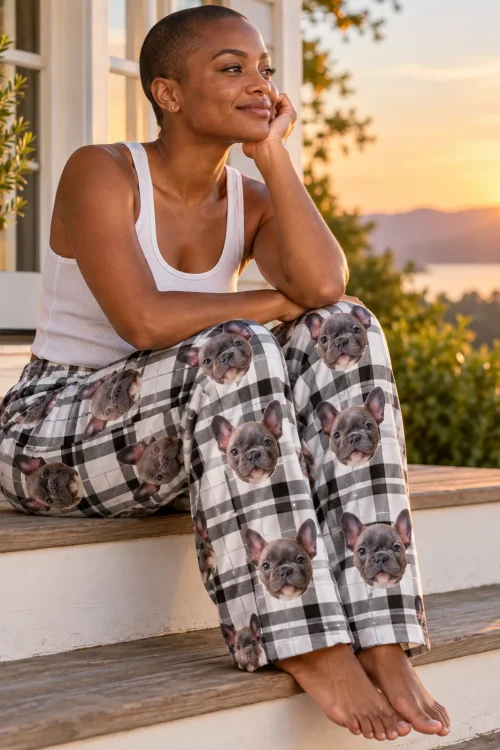Woman on porch steps at sunset in black and white plaid pajama pants with French bulldog faces