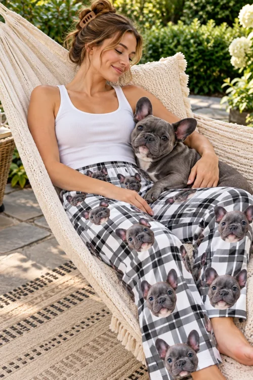 Woman relaxing in a garden hammock with a French bulldog, wearing black and white plaid pajama pants