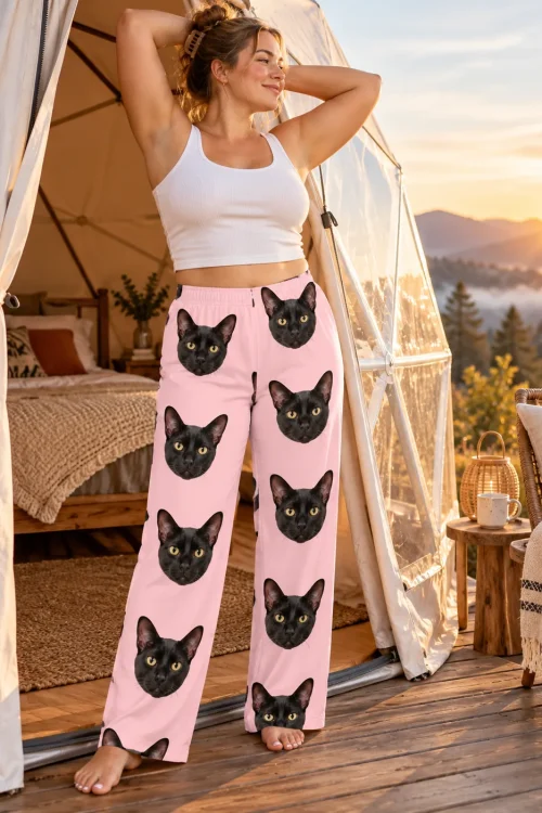 Woman stretching at a glamping dome at sunrise in blush pink black cat pajama pants, mountains behind her