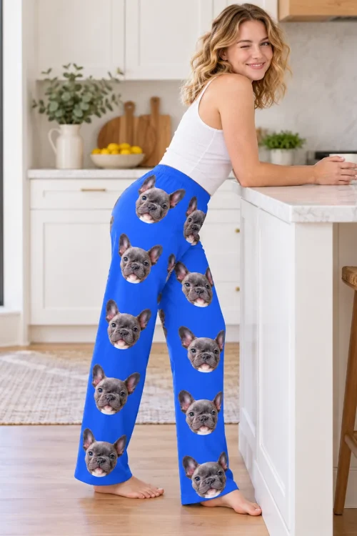Woman leaning on a kitchen island in royal blue pajama pants covered in French bulldog faces