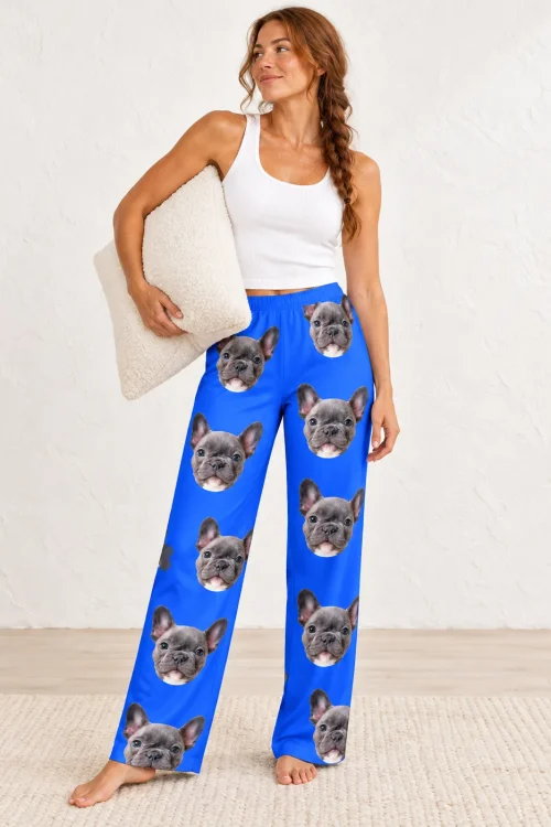 Woman holding a pillow in royal blue pajama pants printed with French bulldog faces