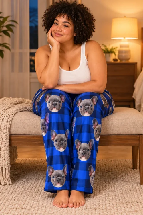 Woman on a bedroom bench in blue plaid pajama pants covered in French bulldog faces