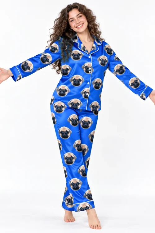 Woman with long curly hair, arms open wide, in royal blue satin pajamas printed with pug faces