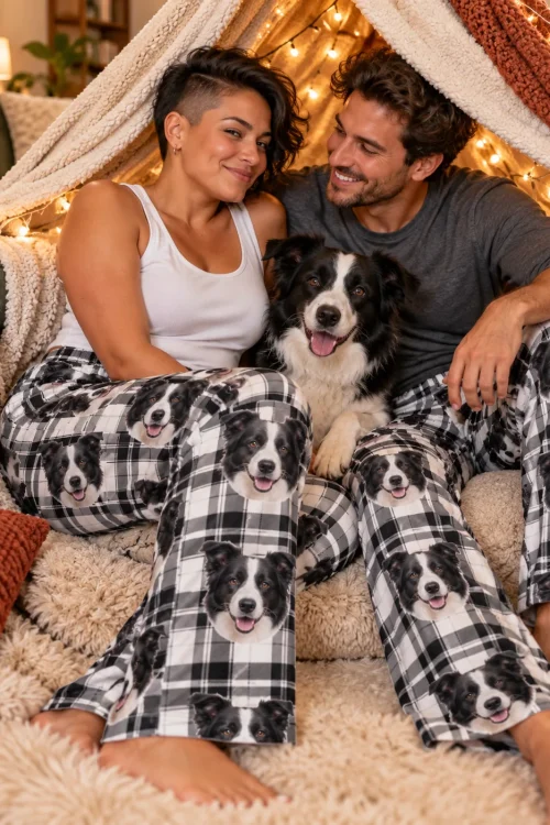 Couple and their border collie in a blanket fort with string lights, both in white plaid collie pajama pants