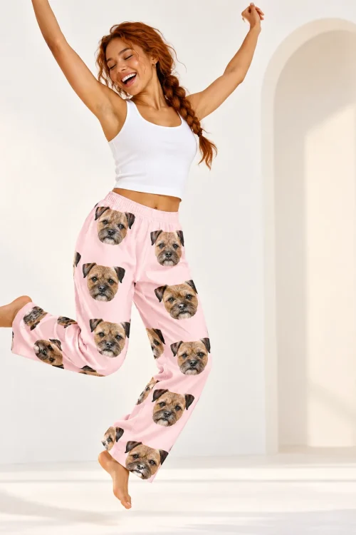 Woman with a red braid leaping barefoot in blush pink border terrier pajama pants, white arched studio