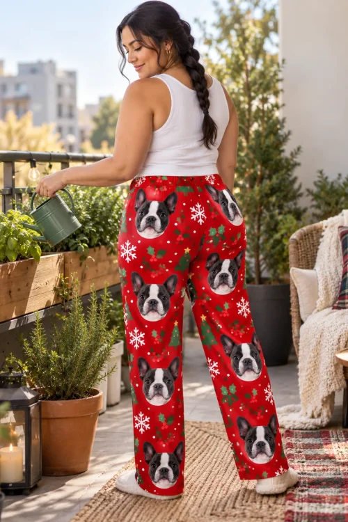 Woman in a long braid watering balcony herbs, seen from behind, in Christmas red Boston terrier pajama pants