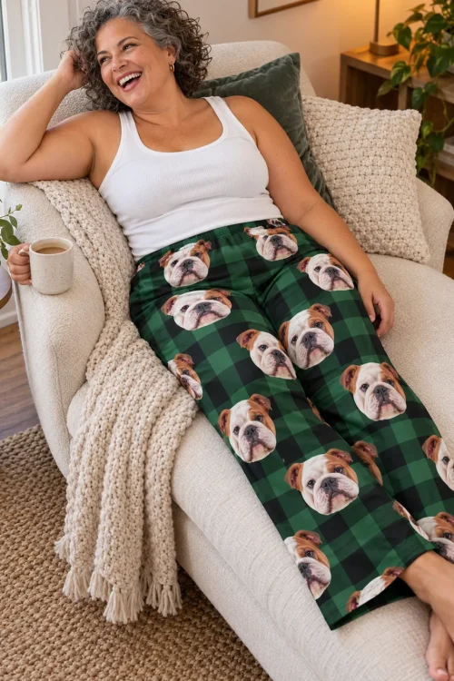 Laughing woman reclining on a cream chaise with coffee, in green plaid bulldog pajama pants