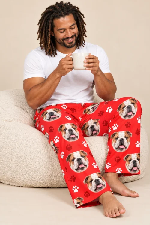 Man with locs sipping from a mug on a cream bean bag in red paws bulldog pajama pants