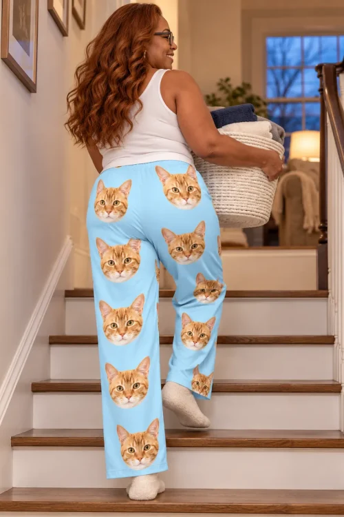 Woman carrying a laundry basket upstairs in light blue cat pajama pants, back view