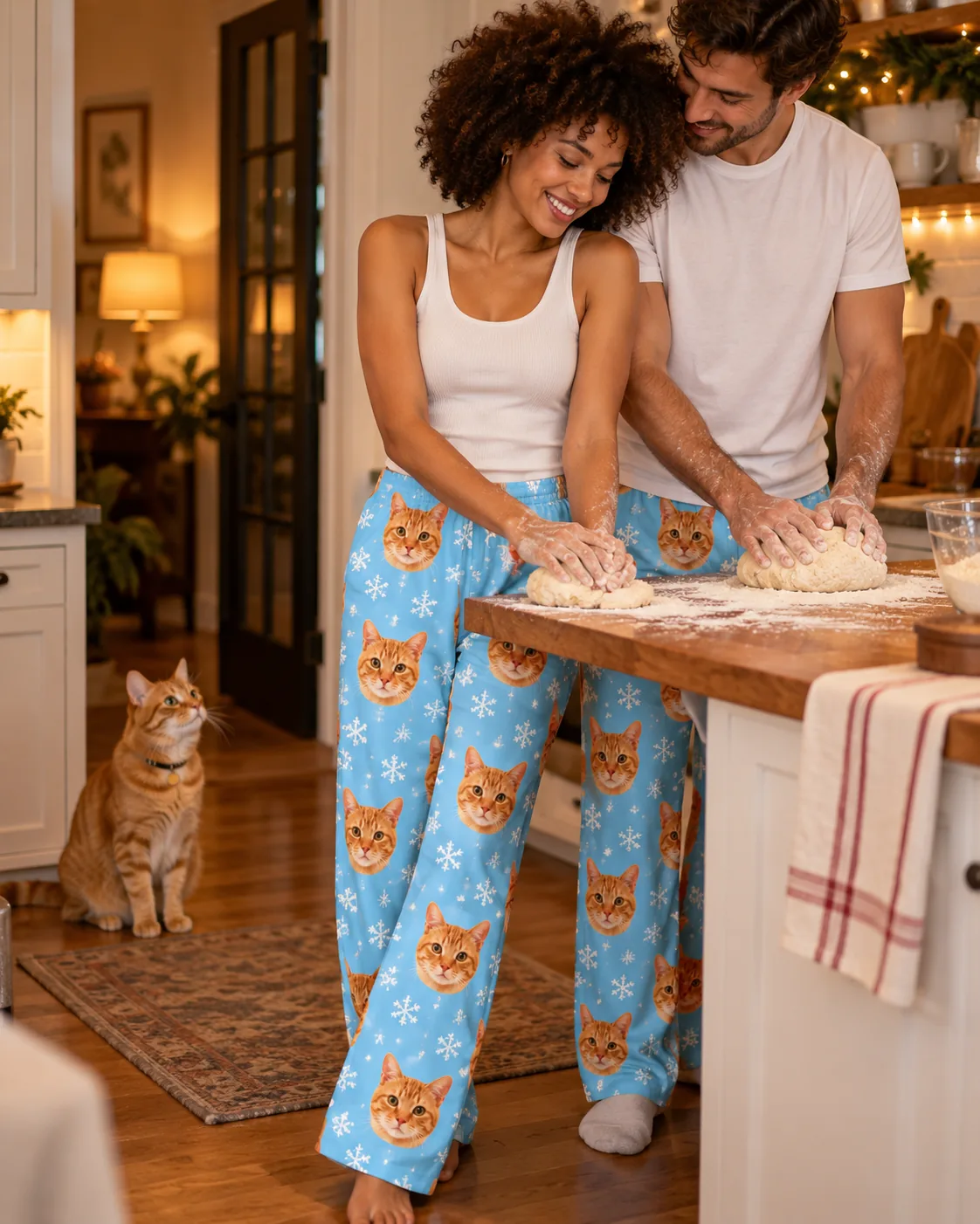 Women's Custom Cat Face Pajama Pants — snowflake family | GenzOutfit Couple kneading dough in the kitchen in snowflake cat pajamas while their tabby watches