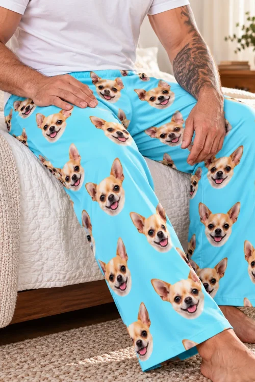 Man seated on the edge of a bed in light blue chihuahua pajama pants, close-up of the print