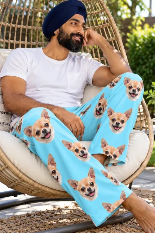 Man relaxing in a hanging wicker chair in a garden, wearing light blue chihuahua pajama pants for men