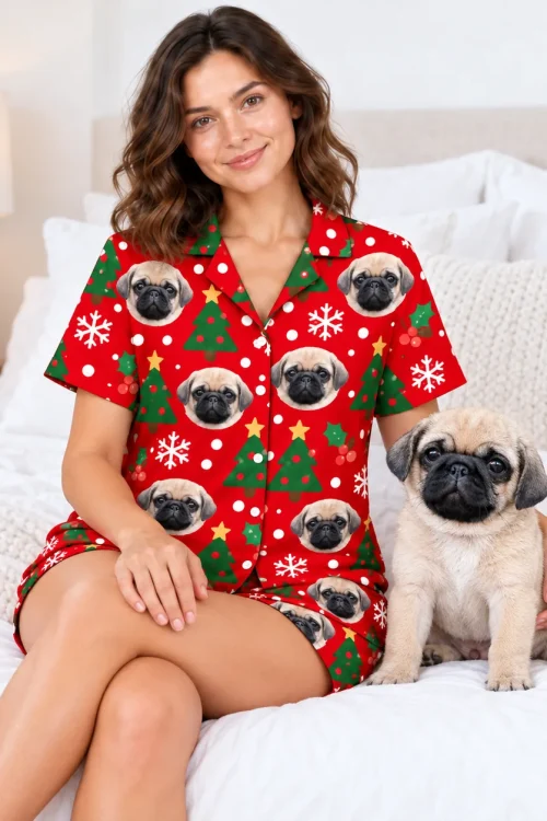 Woman sitting on a bed beside her pug, wearing the red Christmas pet face pajama set