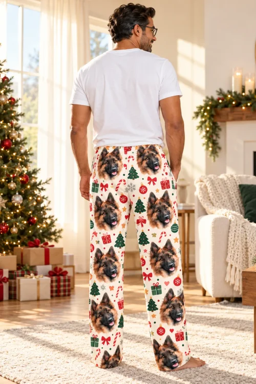 Back view of a man in cream Christmas pajama pants with German Shepherd faces by a decorated tree