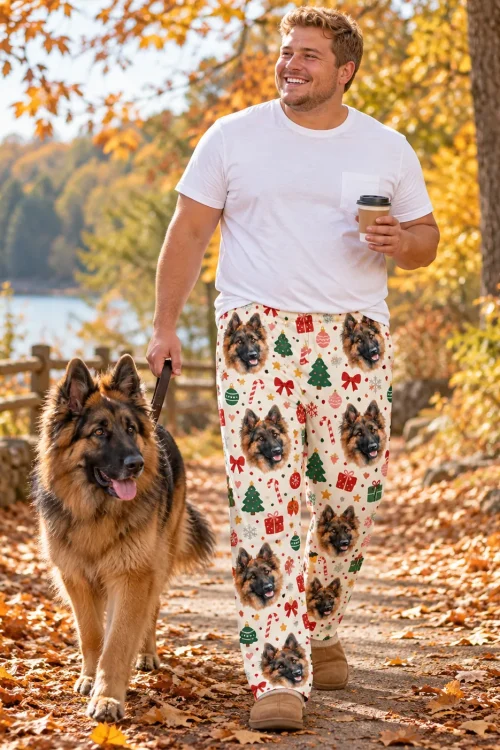 Man walking his German Shepherd on an autumn path in cream Christmas pajama pants with the dog's face