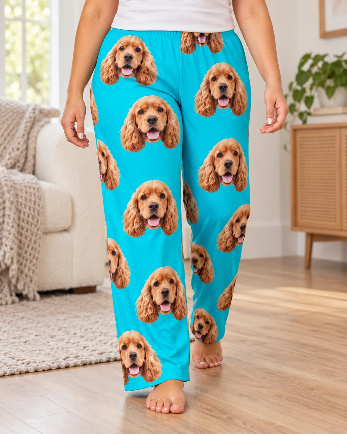 Woman walking barefoot across a wood floor in teal pajama pants printed with cocker spaniel faces