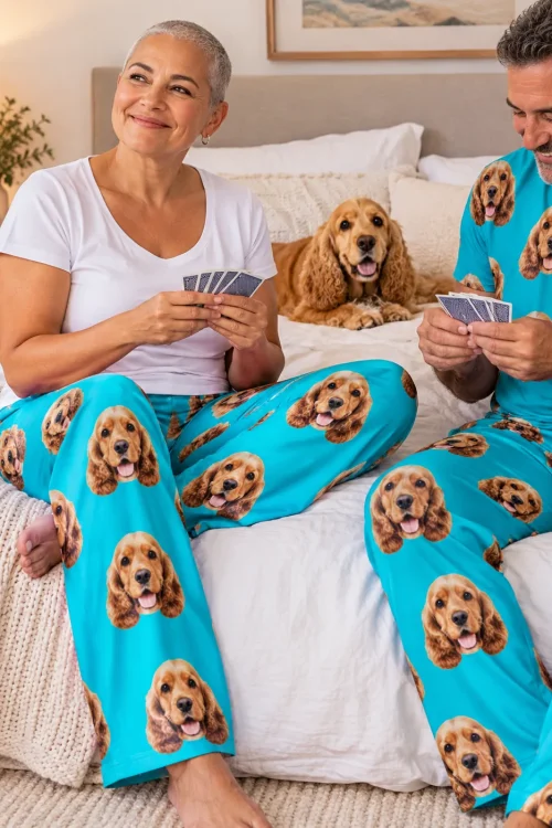 Couple playing cards on a bed in teal cocker spaniel pajamas, a golden cocker resting between them