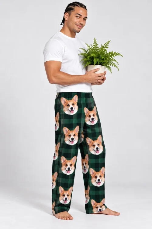 Man holding a potted fern, side view, in green plaid corgi pajama pants with rows of corgi faces, light grey studio