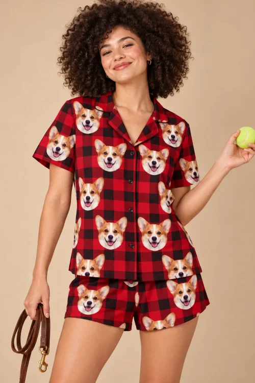 Woman holding a tennis ball and a leash in a red plaid corgi pj set against a warm tan backdrop
