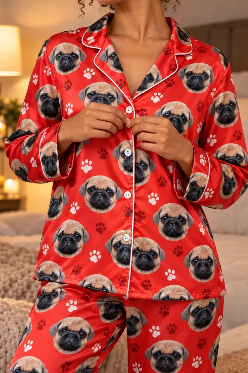 Close-up of a woman buttoning a red satin pajama shirt printed with pug faces, paws and white piping