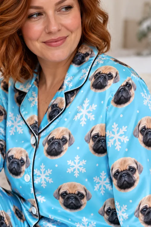 Close-up of a light blue satin pajama shirt with pug faces, white snowflakes and black piping