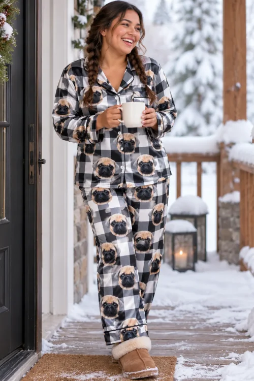 Woman with a mug on a snowy porch in a white and black plaid satin pajama set printed with pug faces