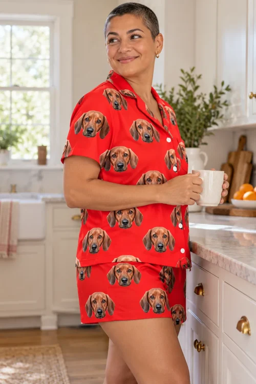 Woman holding a mug at the kitchen counter in a red dachshund pajama set, side view of shirt and shorts