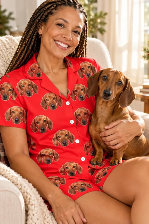 Woman on an armchair hugging her dachshund, in a red short-sleeve dachshund pajama set