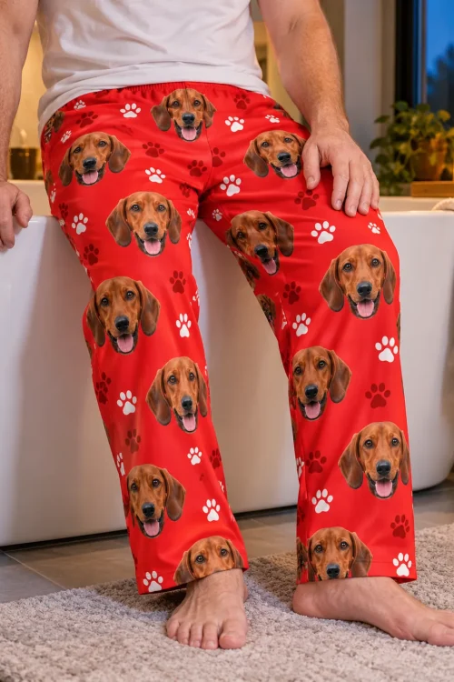 Man sitting on the edge of a bathtub, close view of red paws men's dachshund pajama pants