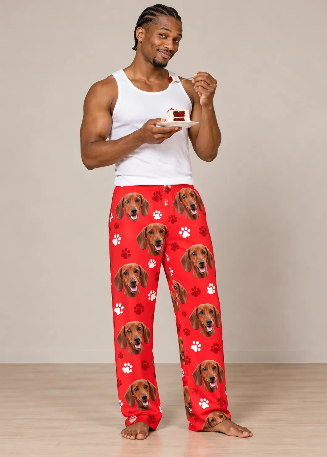 Man in a white tank eating red velvet cake in a studio, wearing red paws dachshund pajamas for men