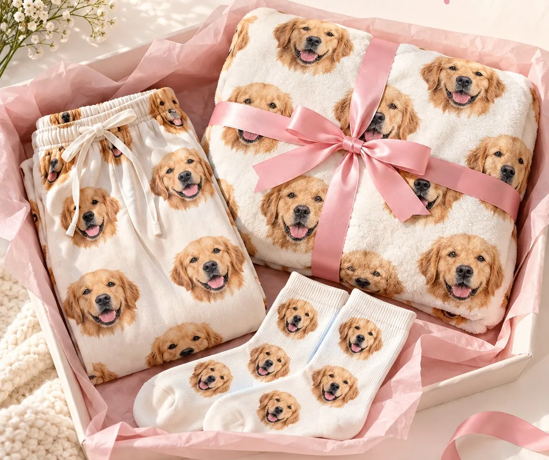 Pink gift box of dog mom gifts: pajama pants, a ribbon-tied blanket and socks printed with a golden retriever's face