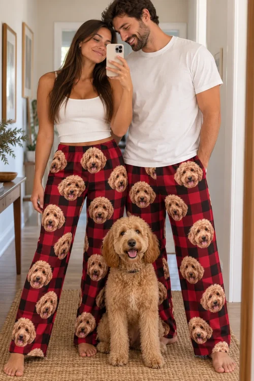 Couple taking a mirror selfie in red plaid doodle pajama pants with their goldendoodle sitting in front