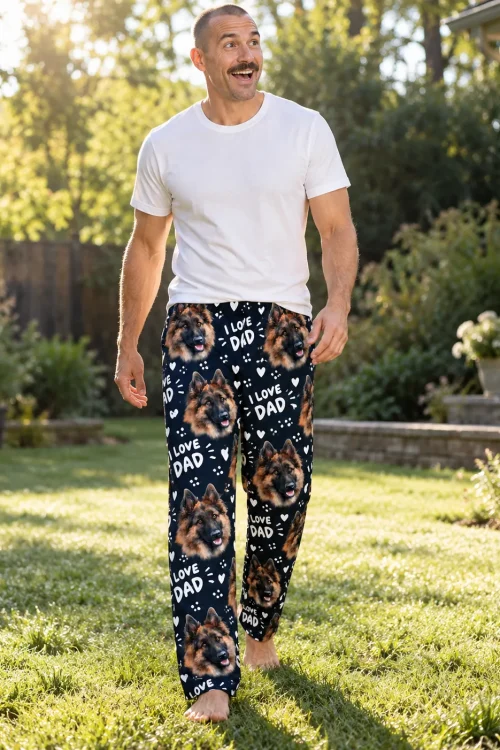 Man walking barefoot across a sunny lawn in navy Father's Day pajama pants with German Shepherd faces