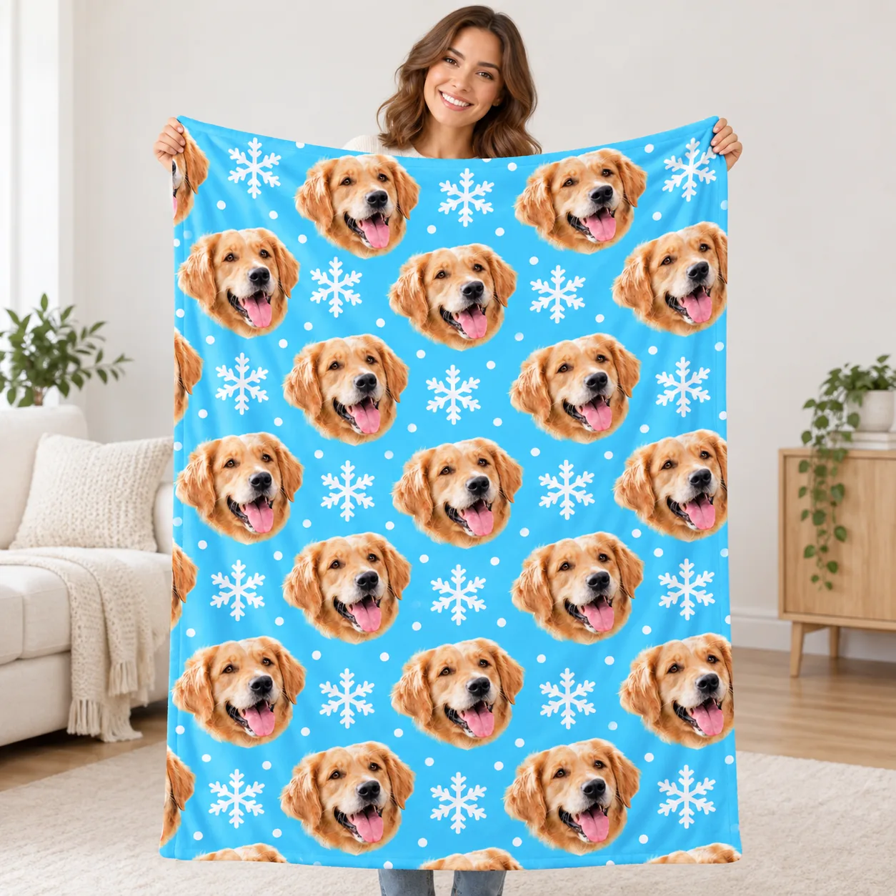 Woman holding up a portrait fleece blanket printed with golden retriever faces and snowflakes to show its size