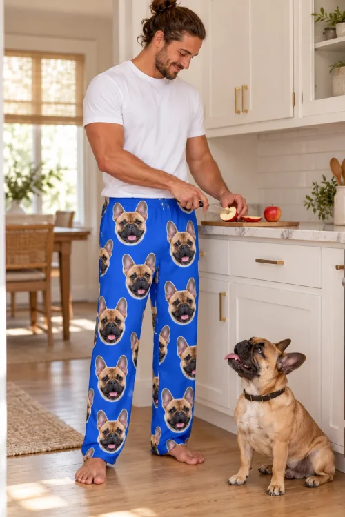 Man slicing apples in a white kitchen as his Frenchie looks up, in royal blue French bulldog pajamas