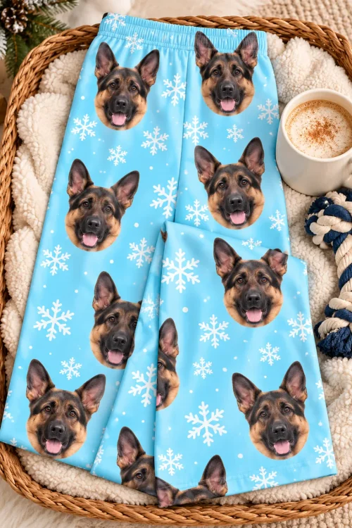 Snowflake german shepherd pajama pants folded in a wicker basket with cocoa and a rope dog toy