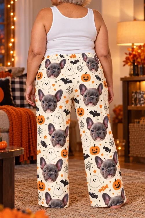 Back view of a woman in cream Halloween pajama pants with French bulldog faces in a decorated room