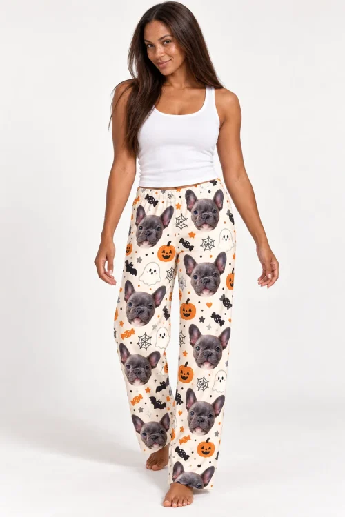 Smiling woman walking in cream Halloween pajama pants printed with French bulldog faces and pumpkins