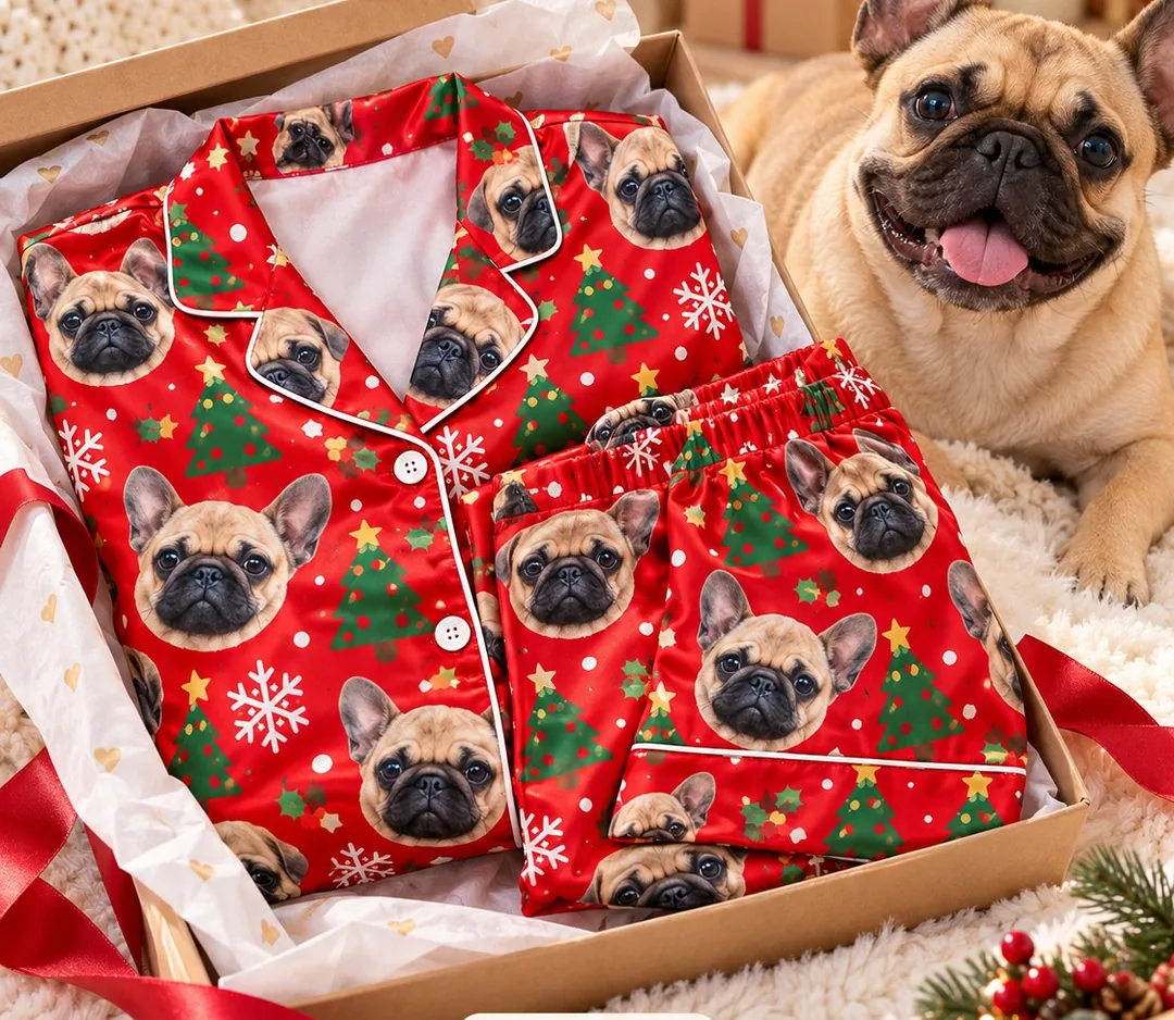 Red Christmas pajama set printed with French bulldog faces in a gift box beside a French bulldog, a dog owner gift