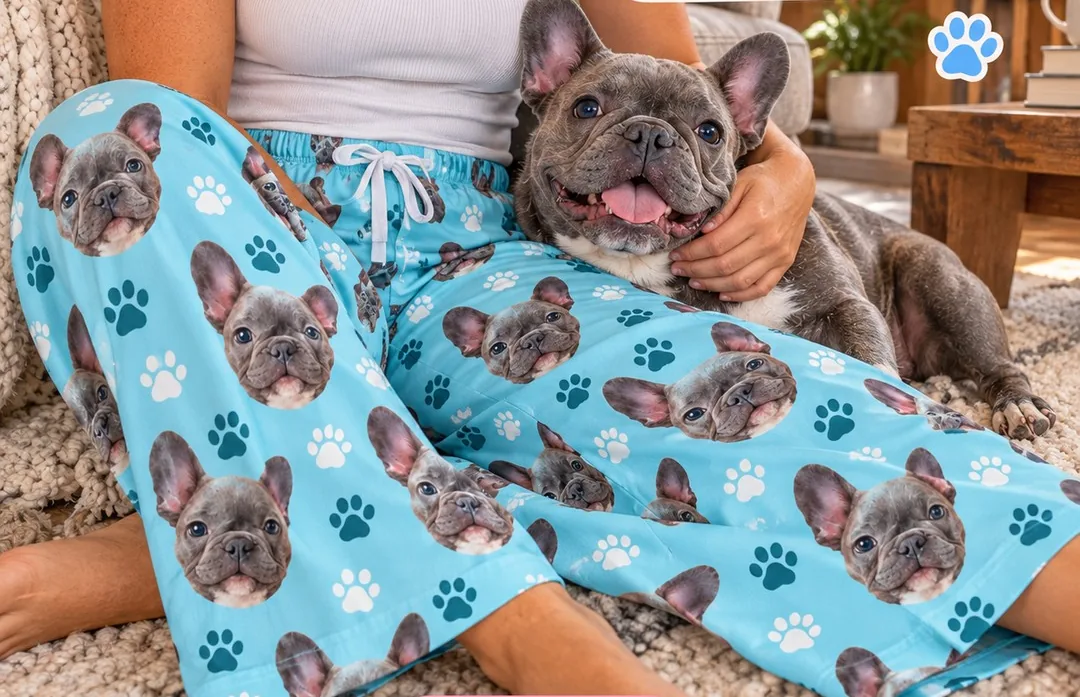 Light blue pajama pants printed with French bulldog faces and paw prints, a gift for dog owners, her dog resting on her lap