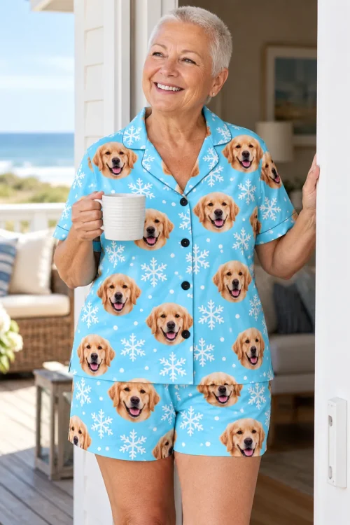Silver-haired woman with a mug in a beach house doorway wearing a snowflake golden retriever pajama set