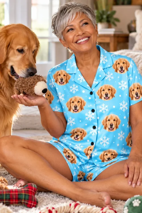 Smiling woman offering a plush toy to her golden retriever, in a snowflake golden retriever pj set