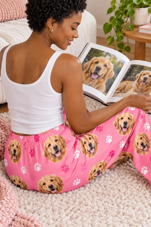 Woman on a rug looking at a golden photo book in pink paws golden retriever pajama pants, back view