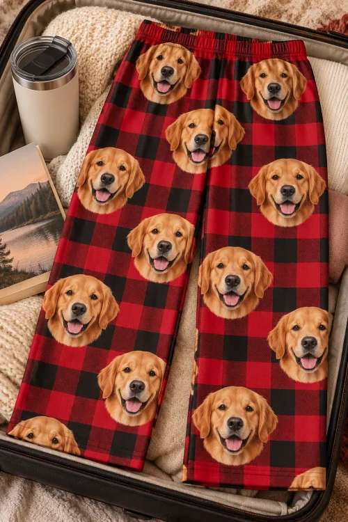 Red plaid golden retriever pajama pants laid in an open suitcase next to a tumbler and a book